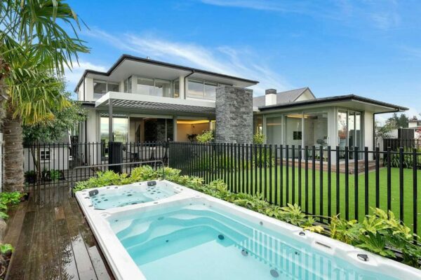 Rear view of a luxurious custom home with spa pool and outdoor living area—expert home builders in Christchurch delivering high-end property transformations.