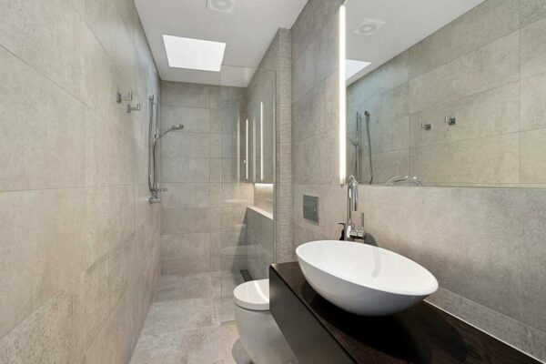 Modern tiled bathroom renovation by Stanton Builders with a vessel sink and skylight