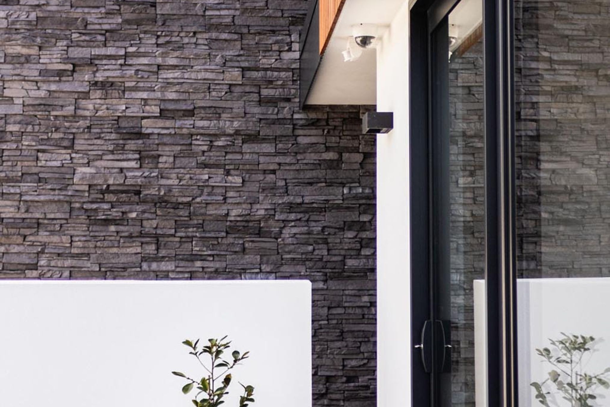 Detail of stacked stone cladding and large glass doors on a home exterior—exemplifying Stanton Builders’ craftsmanship in architectural builds, extensions, and renovation work, trusted by master builders in the region.