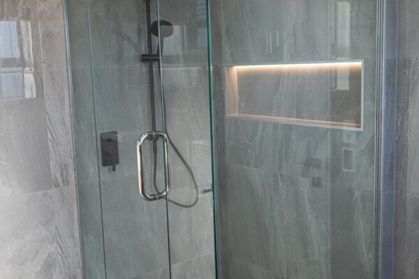 Luxury glass shower enclosure with black matte hardware designed by Stanton Builders