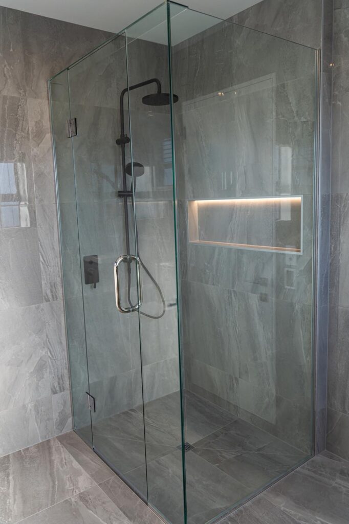 Luxury glass shower enclosure with black matte hardware designed by Stanton Builders