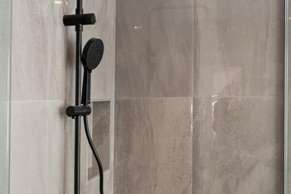 Close-up of modern black rain shower head and fittings in Stanton Builders' bathroom renovation