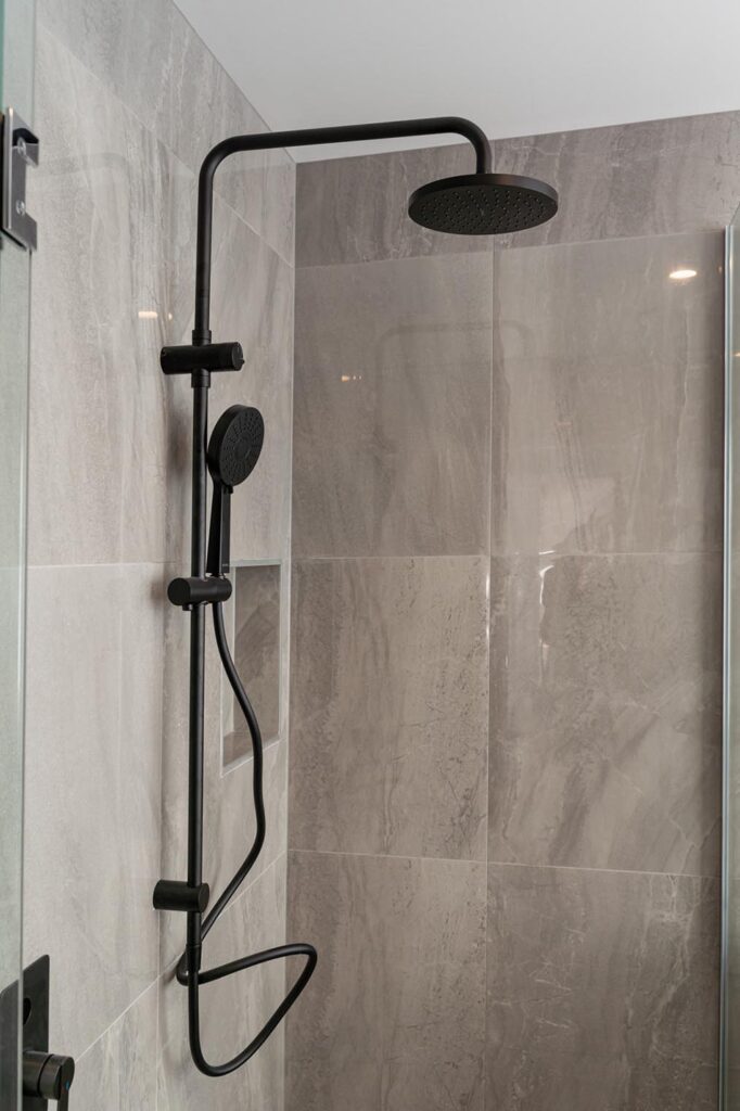 Close-up of modern black rain shower head and fittings in Stanton Builders' bathroom renovation