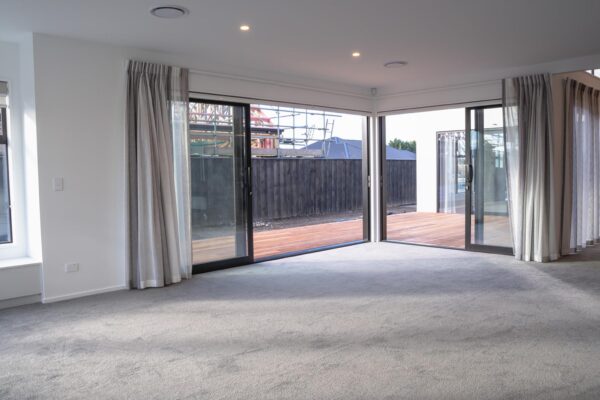 Open-plan living room with floor-to-ceiling sliding glass doors by Stanton Builders