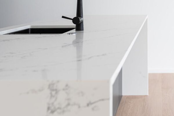 Minimalist kitchen island with marble benchtop and black tapware by Stanton Builders