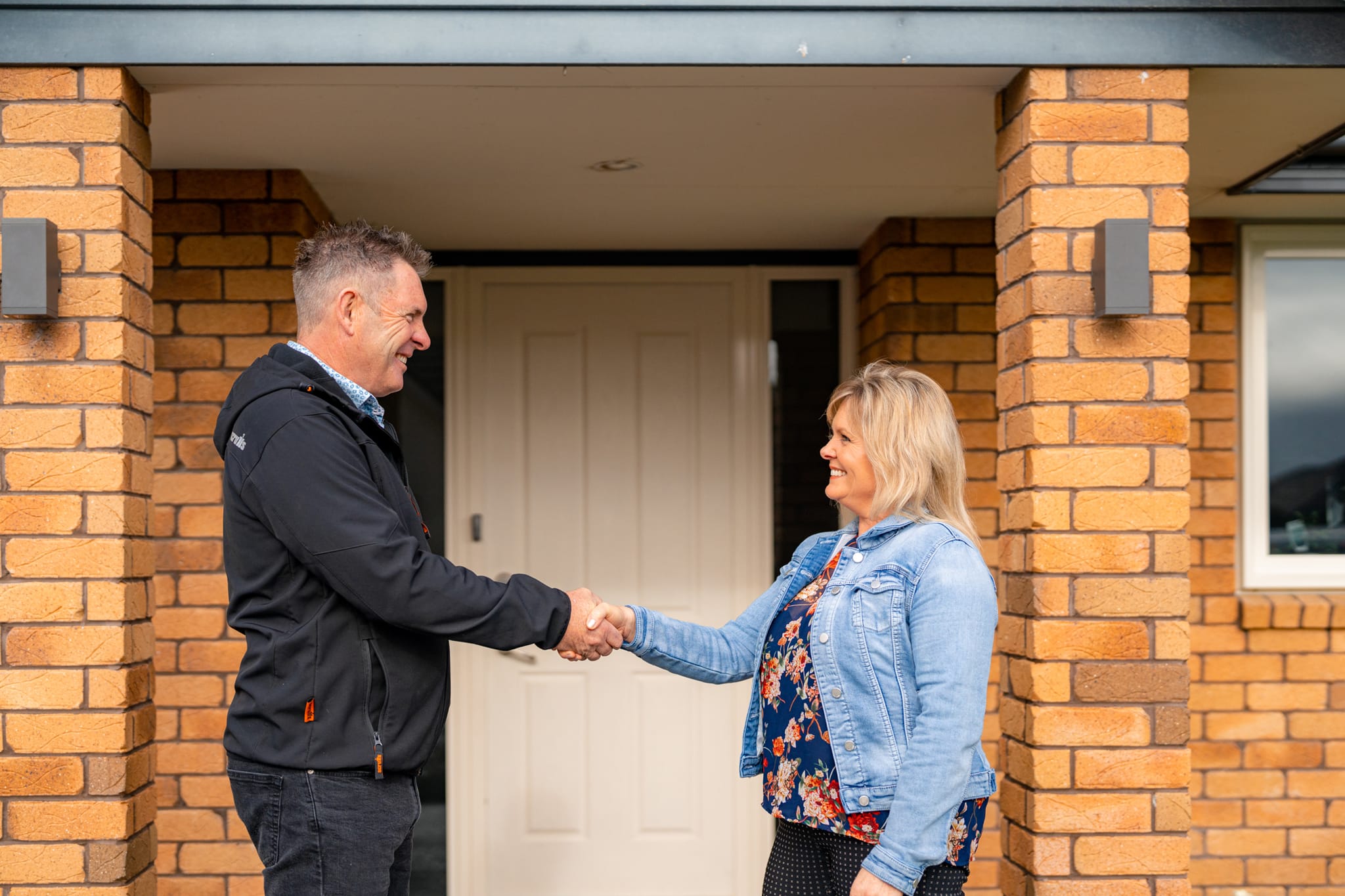 Brent shaking hands with a happy client outside their renovated home, demonstrating Stanton Builders’ commitment to customer satisfaction and renovation excellence.