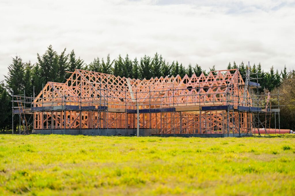 Distant view of house framing nestled among trees, built by Stanton Builders—home extension builders known for quality craftsmanship and architectural builds.