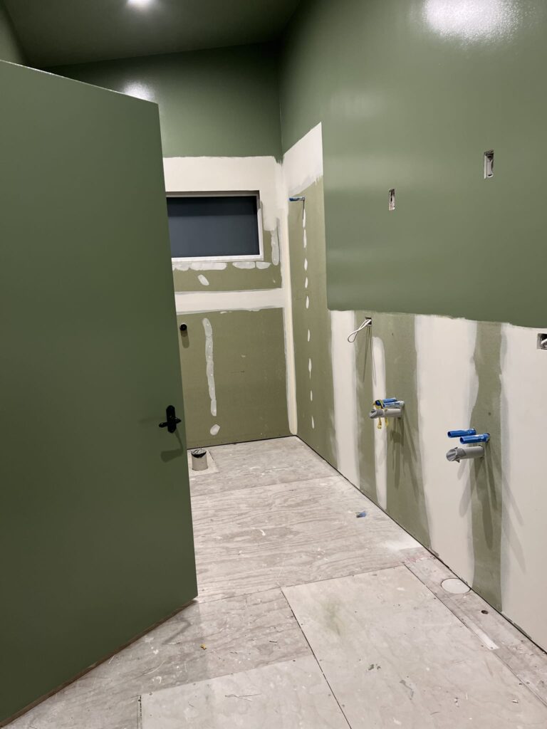 Bathroom renovation in progress with green feature walls, part of a home renovation project by Stanton Builders in Canterbury.