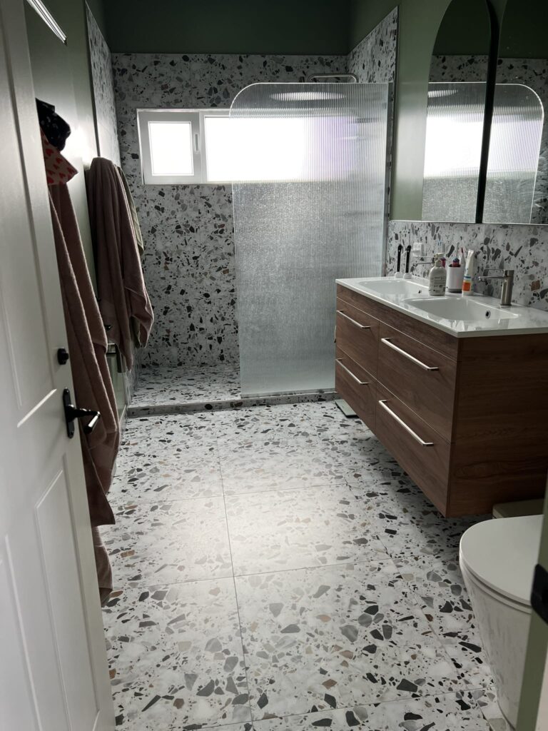 Completed bathroom renovation featuring terrazzo tiles, timber vanity, and glass shower by Stanton Builders, Canterbury renovation specialists.